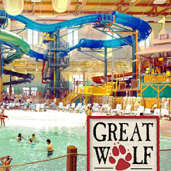 Indoor pool and water slides with people playing in water.