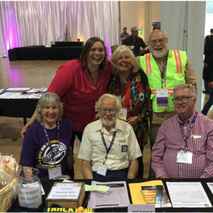 Group of members of retiree local posing at a conference, some wearing SEIU lanyards and t-shirst