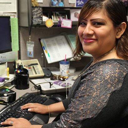 A woman smiling at a desk in a state worker cubicle