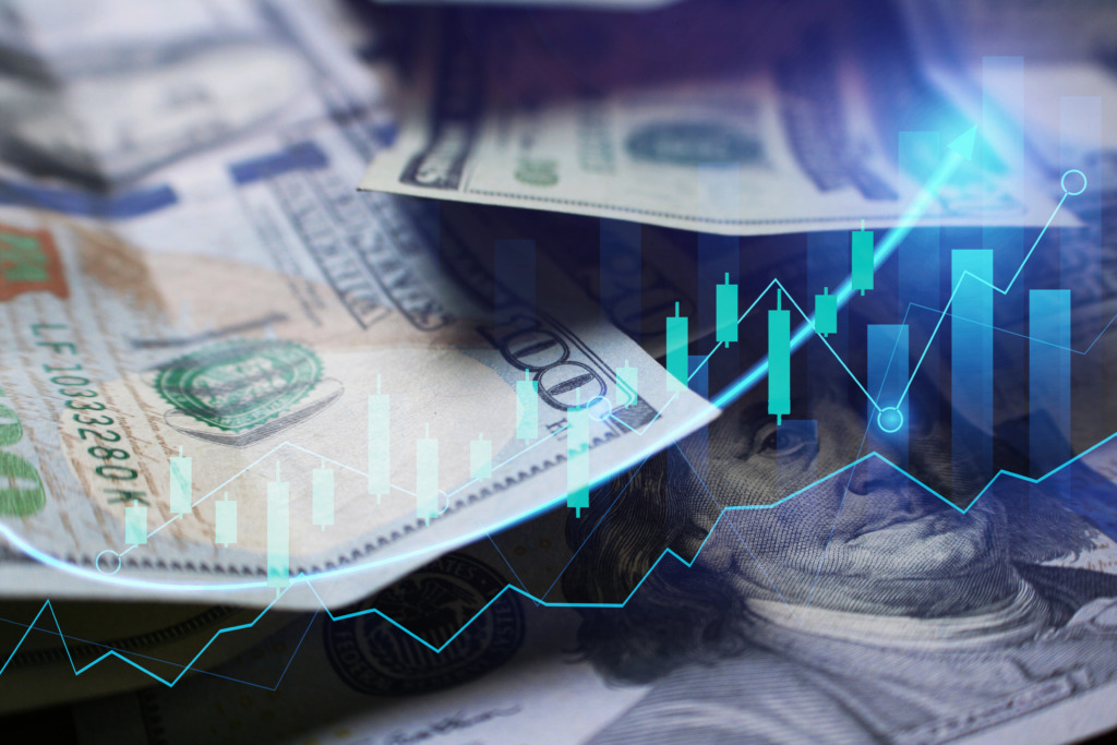 An image of hundred dollar bills with stock market graphs superimposed on top of them.