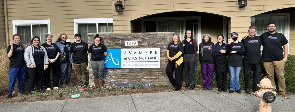 A group of workers wearing SEIU Nursing Home Union t-shirts standing in front of an assisted living facility with a sign that says Avamere at Chestnut Lane