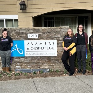 A group of workers wearing SEIU Nursing Home Union t-shirts standing in front of an assisted living facility with a sign that says Avamere at Chestnut Lane