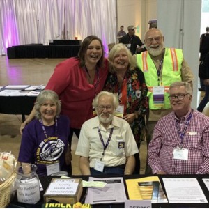 A group of SEIU 503 retirees sitting at a table at a union conference, wearing name badges on purple lanyards